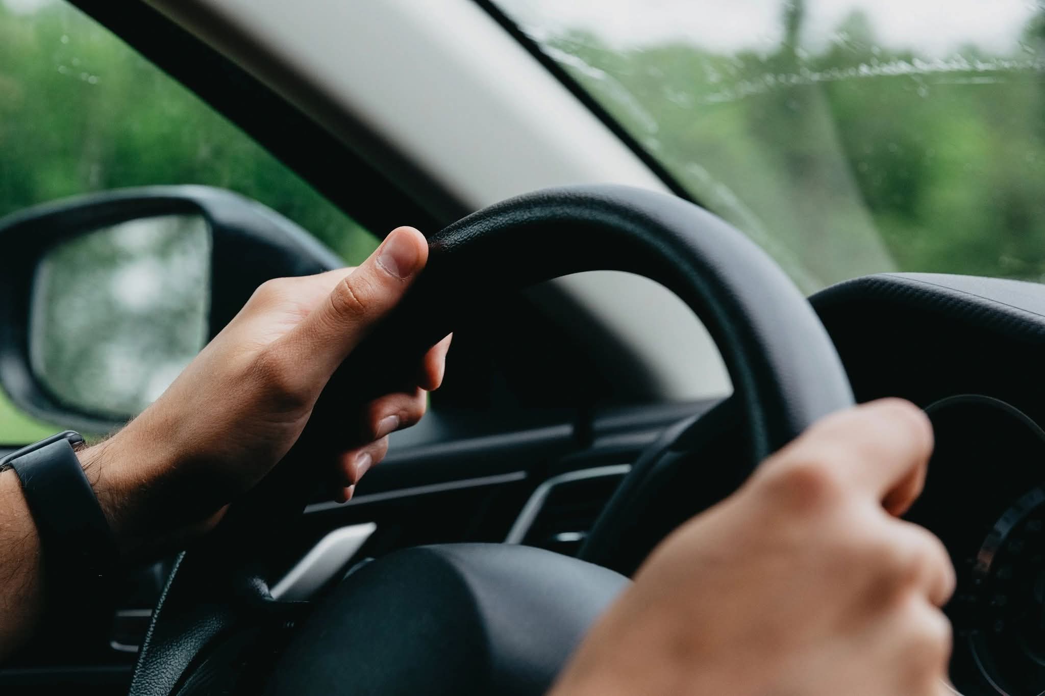 image of two hands on a vehicle steering wheel